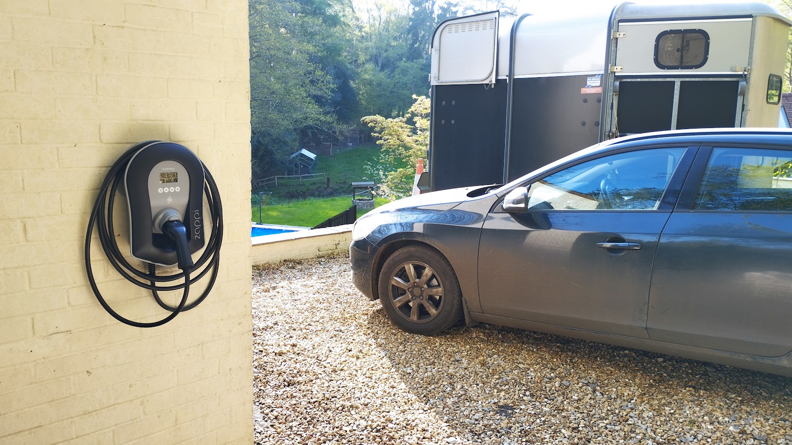 Zappi charger on a rural driveway — tethered install positioned for easy connection to the vehicle.